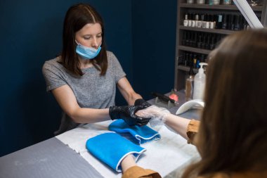 Spa Salonu. Manikür. Parafin El Banyosu. Parafin tedavisini uygulayın. Kase, katkı maddesi. Balmumu küvet bakımı. Tırnak bakımı. Tırnak sanatçısı manikür yapıyor. Profesyonel usta eldiveni müşteriye veriyor..