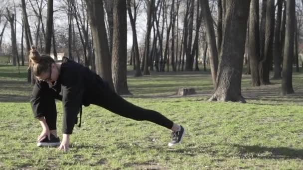 Gesunde junge Asiatin beim Sport im Park. Fit junge Menschen beim Training. Die sportliche junge Frau wärmt sich auf und streckt die Beine vor dem Training im Freien. Sportlerin dehnt sich vor Fitness — Stockvideo