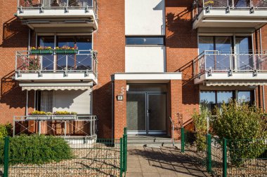 Renkli çiçekleri ve saksıları olan geleneksel Avrupa konutları. Krefeld, Almanya 'da güneşli havada logosu ve balkonları iyi korunmuş bir konut binasının cephesi.