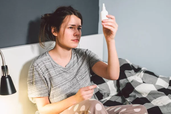 テーマは季節性の風邪 鼻水鼻インフルエンザ ウイルス感染症です 自宅ベッドで若い白人女性は 彼女の鼻に鼻水の薬の噴霧滴を使用します Renitis アレルギー性副鼻腔炎 — ストック写真