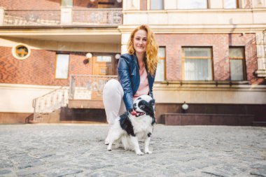 Kadın ve köpek. Dışarıda, mutlu. Tema, insan ve hayvanın arkadaşlığı. Chihuahua 'lı kız. Genç kadın ve köpeği Chihuahua sokakta yürüyorlar. Köpek tasmasını çekiyor..