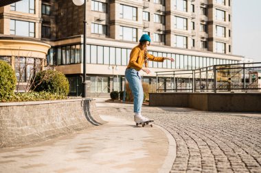 Şehirde kaykay yapmak. Kadın, eğlence. Hippi kız kaykay yapıyor. Sür, stil. Aşırı spor ve duygu konsepti. Alternatif yaşam tarzı. Şehirde kaykay yapan kadın..