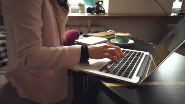 Vista superior de cerca de los womans caucásicos manos Casualmente vestido estudiante, blogger, escritor que trabaja en un portátil que tiene un teléfono en su mano, dentro de la cafetería una mesa de madera y una taza de café. — Vídeos de Stock
