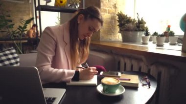 İş kadını cep telefonuyla uzaktan konuşuyor. Bir kafede çalışan meşgul bir iş kadını telefonda konuşuyor. Serbest çalışan biri. Online eğitim. Serbest konsept