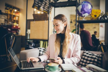 Cafe Table 'da oturan dizüstü bilgisayar kullanan güzel, serbest çalışan bir kadın. İş kadını el yazısı, bilgisayarla iş bağlantısını kullanarak bilgi topluyor. Kafe 'de çalışan güzel bir kadın..