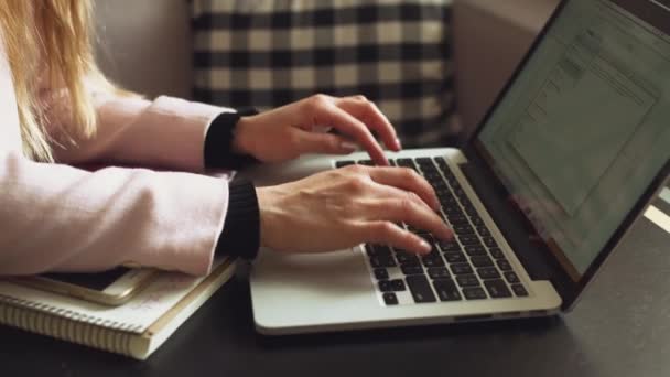 Mujer de negocios independiente que trabaja en el ordenador portátil portátil y teléfono móvil, con taza de café en la mesa de madera en la cafetería. Chica universitaria trabajando en el ordenador portátil durante el descanso de café en la cafetería — Vídeos de Stock