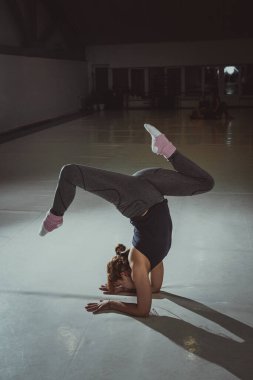 Stüdyoda yoga yapan çekici genç bir kadın. Amuda kalkma egzersizi yapan, salamba sirsasana pozu veren spor kıyafetleri giyen, kapalı alanda uzun süre spor yapan bir kız. Poz verme amuda kalkma, amuda kalkma ve dirsekler.