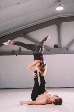 Tema sporu ve sağlıklı bir yaşam tarzı. Akrobasi ve akrobasi. Genç sportif çift akroyoga amuda kalkıyor. Erkek ve dişi akrobatlar Mat 'te akro yoga yapıyorlar. Aile Akroyogası.