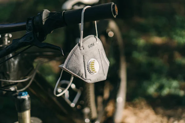 保护碳一次性防毒面具 适用于防烟浓雾颗粒Pm2 森林里一辆山地自行车的把手上挂着一个碳过滤器呼吸器 — 图库照片