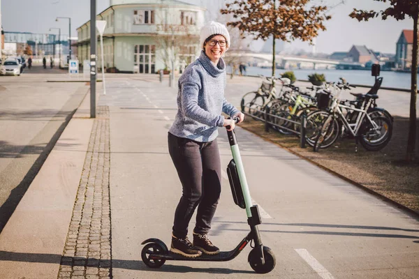 旅游妇女在丹麦首都哥本哈根租电动车 冬日晴天 欧洲街上 女性手持电动踏板车手柄转向柱旋钮 — 图库照片