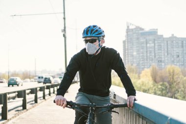 Kirli şehirde koruyucu maske takan bisikletli erkek bisikletçi. Adam işe çevre dostu taşımacılık, kentsel ekoloji raffiği ile gidiyor. Yüz kirliliği maskesi toz bulutu pm2.5 koruma.