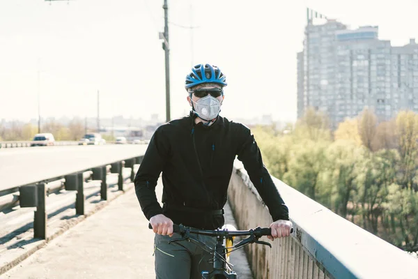 Male cyclist wearing respirator face mask with heavy duty protective filter. Man on bike wearing respirator face mask with heavy duty protective filter. Safety breathing masks. Pollution concept.