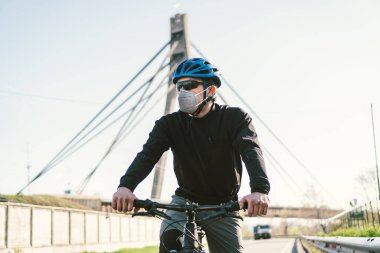 Solunum maskesi takan ve ağır koruyucu filtresi olan bir erkek bisikletçi. Bisikletli bir adam solunum maskesi takıyor ve ağır koruma filtresi takıyor. Güvenli nefes alma maskeleri. Kirlilik kavramı.