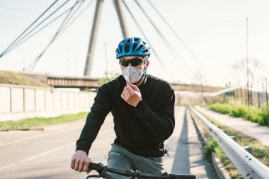 Kirli şehirde koruyucu maske takan bisikletli erkek bisikletçi. Adam işe çevre dostu taşımacılık, kentsel ekoloji raffiği ile gidiyor. Yüz kirliliği maskesi toz bulutu pm2.5 koruma.
