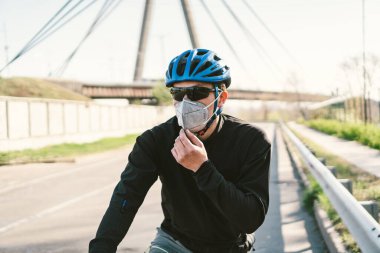 Motosikletli, N95 maskeli, üstü örtülü bir şehirde. Hava kirliliği. Endüstriyel şehir. Tozdan maskeli adam. Solunum cihazındaki adam 2.5 temalı Covid 19. Sis, kirlenmiş zehirli hava, solunum hastalıkları.