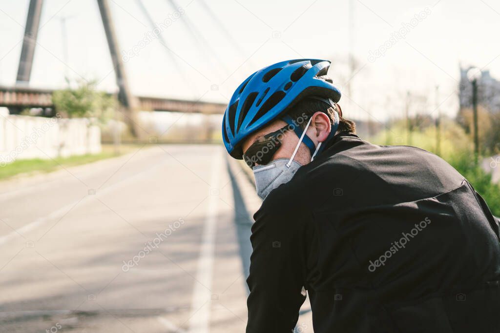 Male cyclist wearing respirator face mask with heavy duty protective filter. Man on bike wearing respirator face mask with heavy duty protective filter. Safety breathing masks. Pollution concept.
