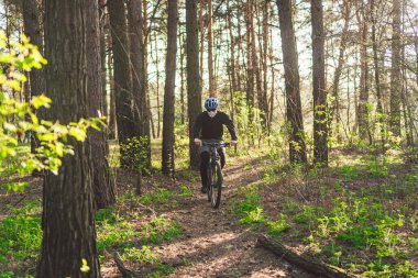 Kirlilik maskesi takan bisikletçi. Solunum cihazındaki 2.5 numaralı filtreyle parka bisikletle giden genç adam. Covid 19 Karantina Sporu. Dağ bisikletçisi ormanda bisiklet sürüyor. Bir patikada dağ bisikleti sürücüsü.