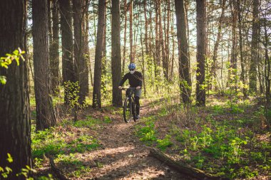 Çevre kirliliğinden koruyucu maskeli genç adam, kır yolunda dağ bisikleti sürüyor. Bisikletçi Ormanda Bisiklete Biniyor. Yüz kirliliği maskesi toz bulutu pm2.5 koruma.
