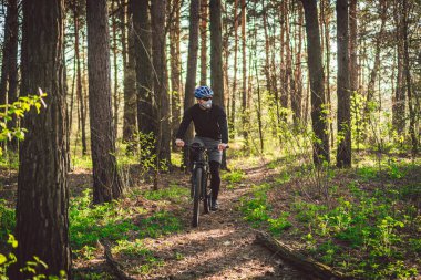 Kirlilik maskesi takan bisikletçi. Solunum cihazındaki 2.5 numaralı filtreyle parka bisikletle giden genç adam. Covid 19 Karantina Sporu. Dağ bisikletçisi ormanda bisiklet sürüyor. Bir patikada dağ bisikleti sürücüsü.