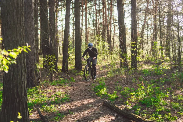 Young man in protective mask from environmental pollution riding mountain bike on cross country road. Cyclist Riding the Bike on Trail in Forest. Face pollution mask smog dust pm2.5 protection.