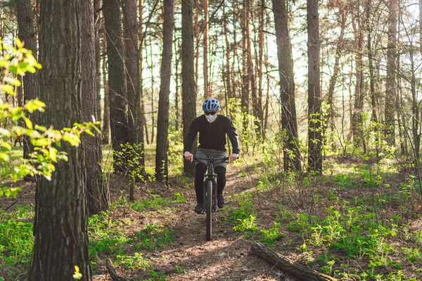 スポーツだ マウンテンバイクサイクリストはシングルトラックに乗っています ヘビーデューティ保護フィルター付きのバイク用マスク顔を身に着けている男 安全呼吸マスク 汚染の概念 森の中でマウンテンバイクに乗る — ストック写真