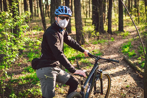 Sport. Mountain Bike cyclist riding single track. Man on bike wearing respirator face mask with heavy duty protective filter. Safety breathing masks. Pollution concept. Riding mountain bike in forest.