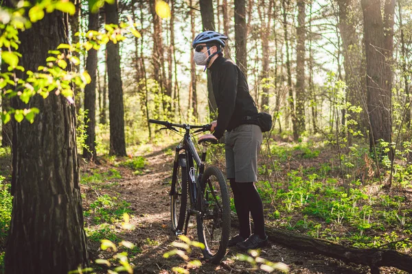 Young man in protective mask from environmental pollution riding mountain bike on cross country road. Cyclist Riding the Bike on Trail in Forest. Face pollution mask smog dust pm2.5 protection.