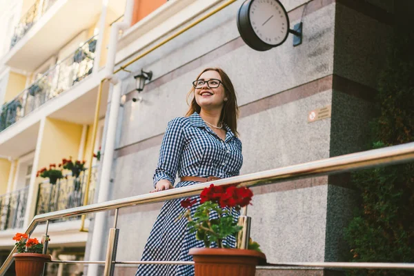 Тема оренди будинку в Європі на літні канікули. Молода кавказька жінка в сукні позує на терасі квартир, прикрашених квітниками з рослинами. Дівчинка біля готелю. — стокове фото