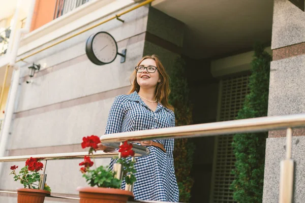 Apartamentos para alugar. Férias Europa Turismo de Viagem. Uma menina de vestido fica perto da entrada de um pequeno hotel europeu acolhedor. Mulher bonita de pé no terraço. Mulher feliz na varanda — Fotografia de Stock