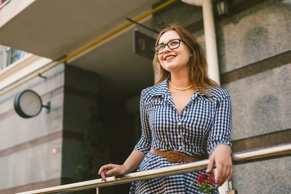 Apartamentos en alquiler. Vacaciones Europa Viajes Turismo. Una chica en un vestido se encuentra cerca de la entrada de un pequeño y acogedor hotel europeo. Hermosa mujer parada en la terraza. Mujer feliz en el balcón — Foto de Stock