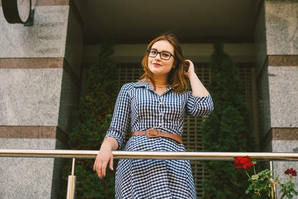 Apartamentos en alquiler. Vacaciones Europa Viajes Turismo. Una chica en un vestido se encuentra cerca de la entrada de un pequeño y acogedor hotel europeo. Hermosa mujer parada en la terraza. Mujer feliz en el balcón — Foto de Stock