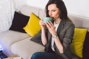 Başarılı orta yaşlı bayan öğretmen çevrimiçi dersten önce kahve içiyor, dizüstü bilgisayarın önünde oturuyor, uzaktan çalışmak için elektronik aletler kullanıyor. Kahve dükkanındaki iş kadını..