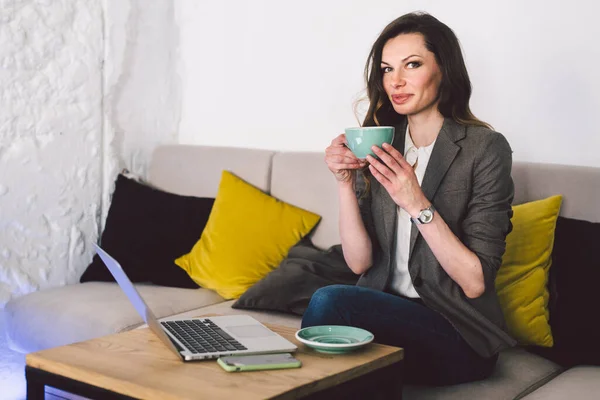 Mujer Mediana Edad Sentada Cafetería Sosteniendo Taza Café Trabajando Ordenador — Foto de Stock