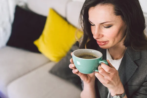 Modern business woman with Cup coffee in workplace. Businesswoman with laptop at cafe. Coffee break for middle-aged lady in office clothes drinks hot drink while working at computer in coffee shop.