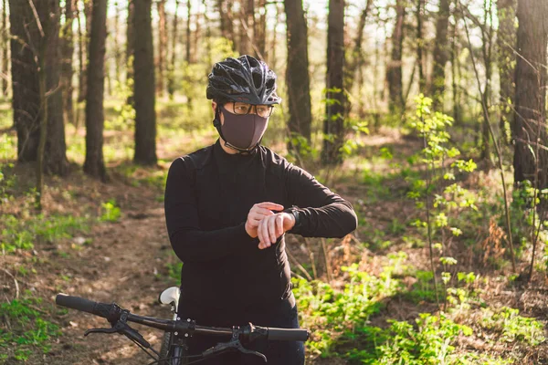 Active sporty woman riding mountain bike on forest trail, wearing a face mask against air pollution and covid19 coronavirus. Cyclist wearing a protective mask. female using face mask in bike.