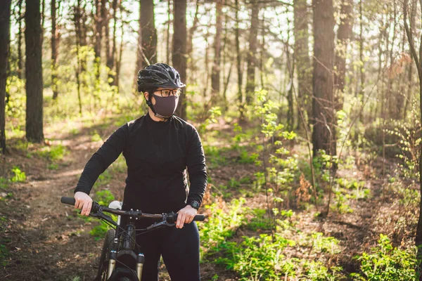 Active sporty woman riding mountain bike on forest trail, wearing a face mask against air pollution and covid19 coronavirus. Cyclist wearing a protective mask. female using face mask in bike.