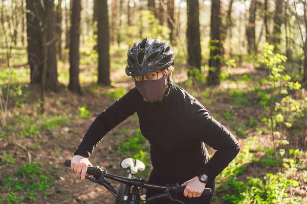 森林道路上の環境汚染乗馬マウンテンバイクから保護マスクの若い女性 公園のトレイル上のサイクリスト乗馬バイク 顔汚染マスクスモッグほこり保護 コロナウイルス Covid — ストック写真