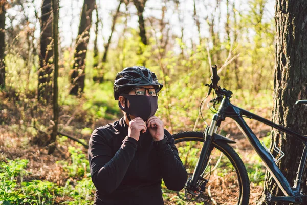 Active sporty woman riding mountain bike on forest trail, wearing a face mask against air pollution and covid19 coronavirus. Cyclist wearing a protective mask. female using face mask in bike.