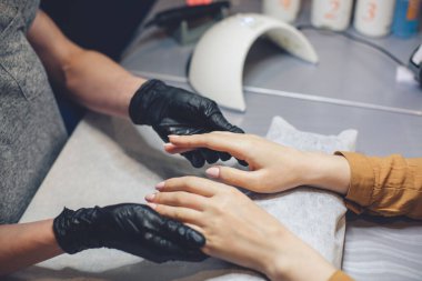 Bir müşteriye nemlendirici ve el masajı yapan bir manikürcünün yakın çekimi. Temamız cilt bakımı ve vücut güzelliği. Spa ve Manikür konsepti. Yumuşak ten. Kozmetik bilimi, uygulama.