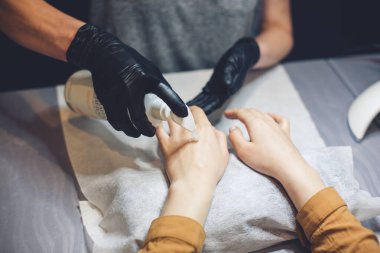 Güzellik uzmanı, müşteri ellerine krem sürüyor. Güzellik salonu. El masajı. Kuaförde manikür. Spa Manikür konsepti. Narin manikürlü ve nemlendirici kremli kadın elleri. Yumuşak ten. El, güzellik..