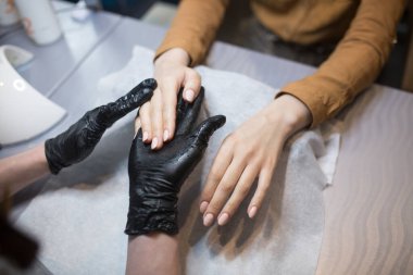 Bir müşteriye nemlendirici ve el masajı yapan bir manikürcünün yakın çekimi. Temamız cilt bakımı ve vücut güzelliği. Spa ve Manikür konsepti. Yumuşak ten. Kozmetik bilimi, uygulama.