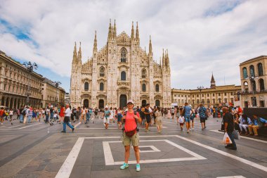 Güneşli bir yaz gününde kalabalık meydanında Duomo di Milano 'nun arka planına poz veren sırt çantalı bir kadın turist. Milan Katedraline Karşı Ayakta Duran Adam İtalya, 15 Temmuz 2017.