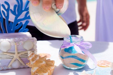 Gelin ve damat, Dominik Cumhuriyeti 'nin Punta Cana kentindeki okyanusun önündeki kumlu sahil nikah töreninde kristal vazoya renkli farklı renkte kumlar döküyorlar.