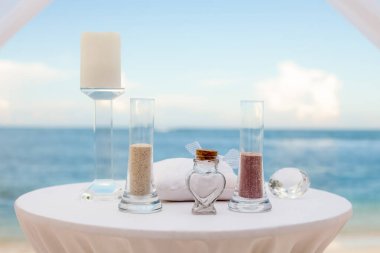 Gelin ve damat, Dominik Cumhuriyeti 'nin Punta Cana kentindeki okyanusun önündeki kumlu sahil nikah töreninde kristal vazoya renkli farklı renkte kumlar döküyorlar.