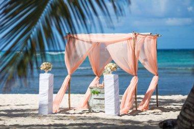 Dominik Cumhuriyeti 'ndeki düğün merasimi için güneşli bir günde kumsalda taze çiçek desenli bambudan yapılmış renkli düğün kemeri çardağı.  