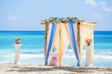 Dominik Cumhuriyeti 'ndeki düğün merasimi için güneşli bir günde kumsalda taze çiçek desenli bambudan yapılmış renkli düğün kemeri çardağı.  