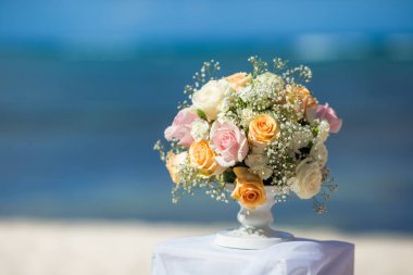 Tropikal bir düğün töreni için kumlu sahilde çiçek buketi.