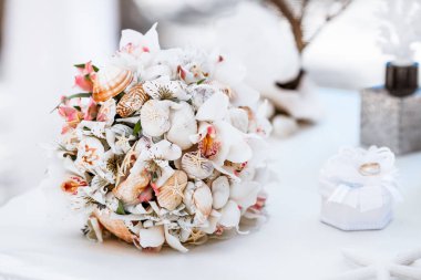 Tropikal bir düğün töreni için kumlu sahilde çiçek buketi.