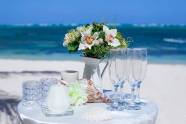 Tropikal bir düğün töreni için kumlu sahilde çiçek buketi.