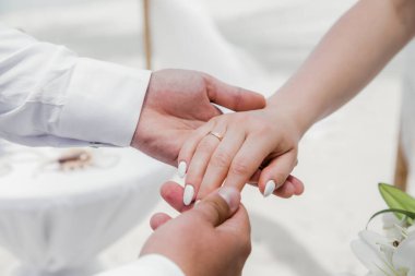 Gelin ve damat, Dominik Cumhuriyeti, Punta Cana 'da okyanusun kıyısındaki kumsalda deniz manzaralı düğün sırasında yüzüklerini değiş tokuş ediyorlar.  